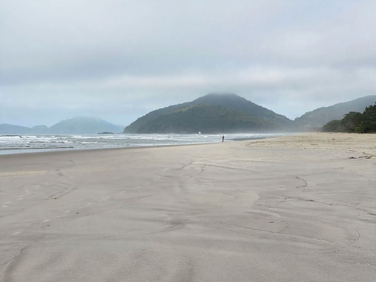 Praia de Itamambuca vazia, com montanhas e neblina ao fundo