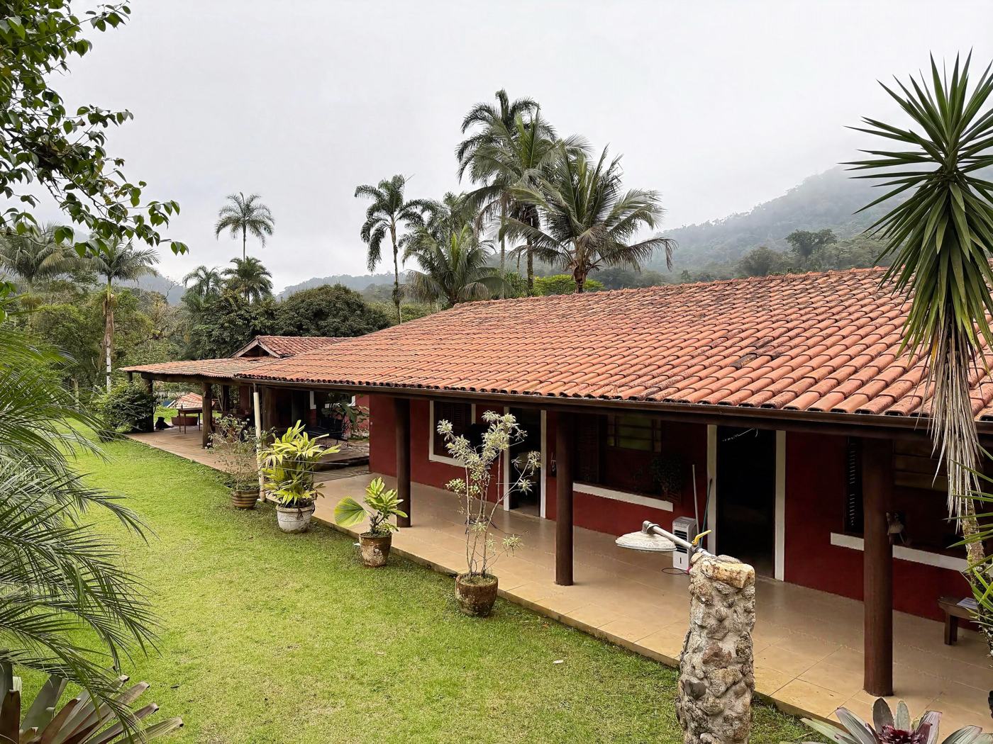 Casa principal da Pousada Damata entre palmeiras e a serra