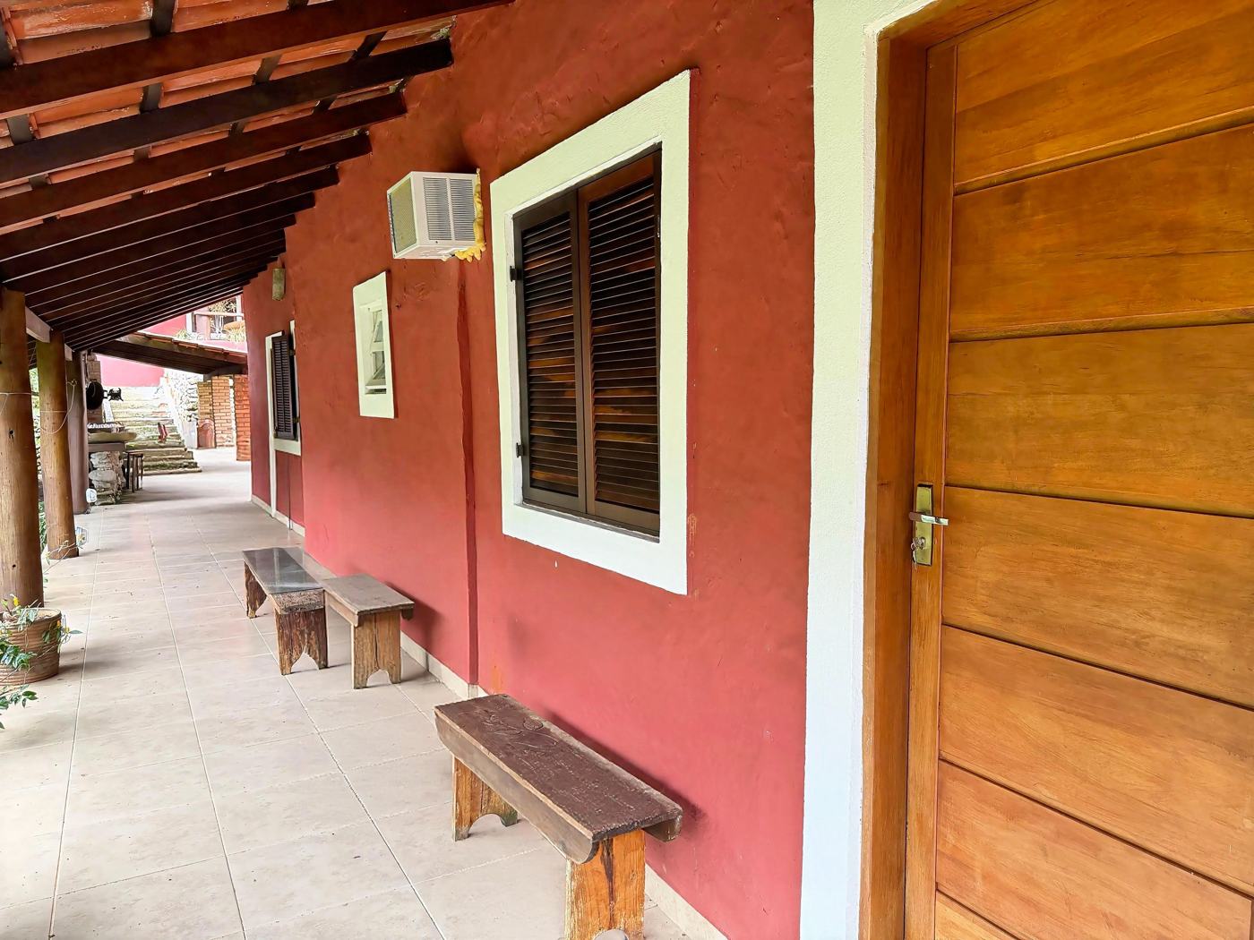 Varanda com bancos de madeira na porta das suítes